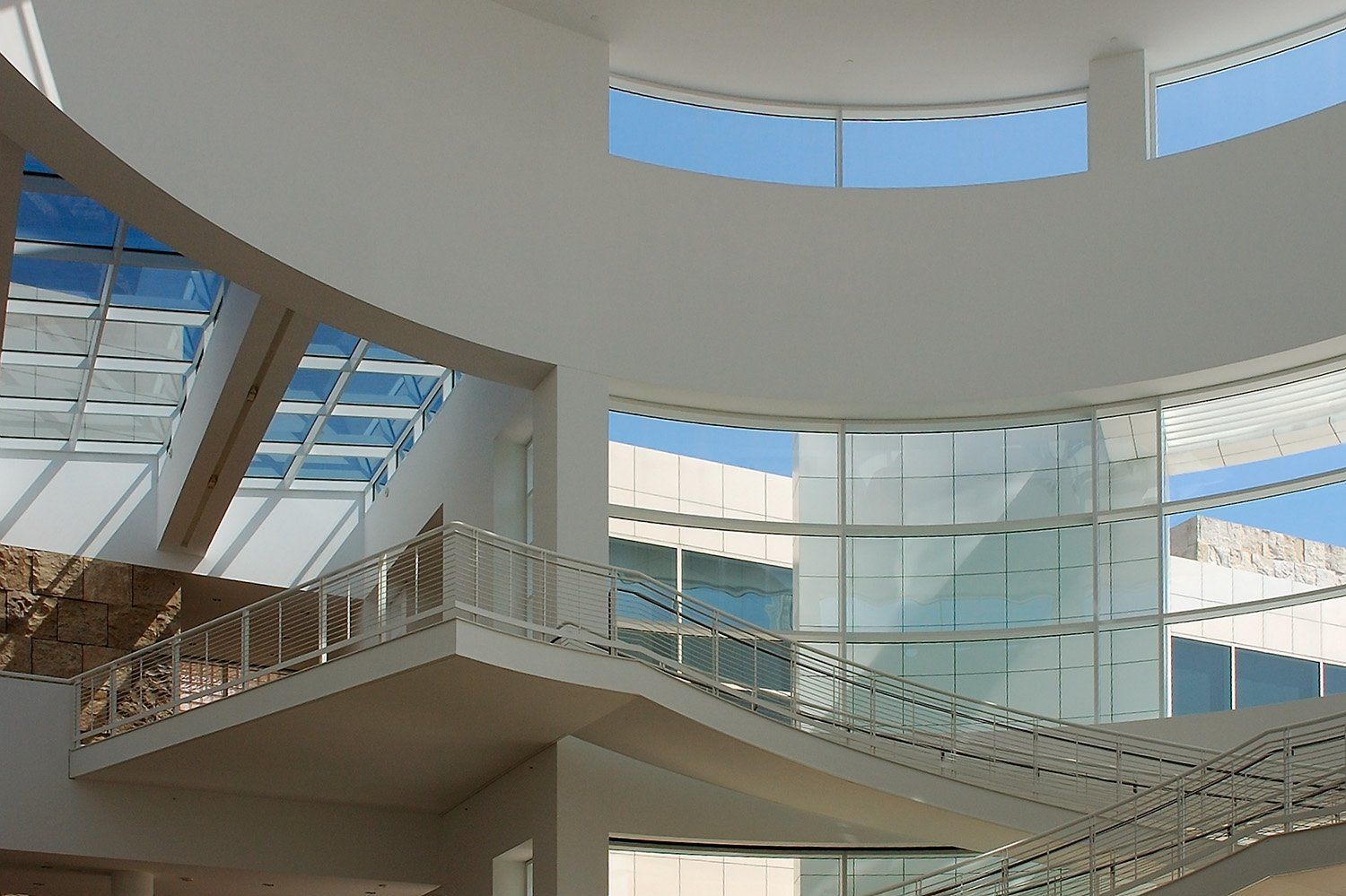A round skylight above curved white walls and stair landings