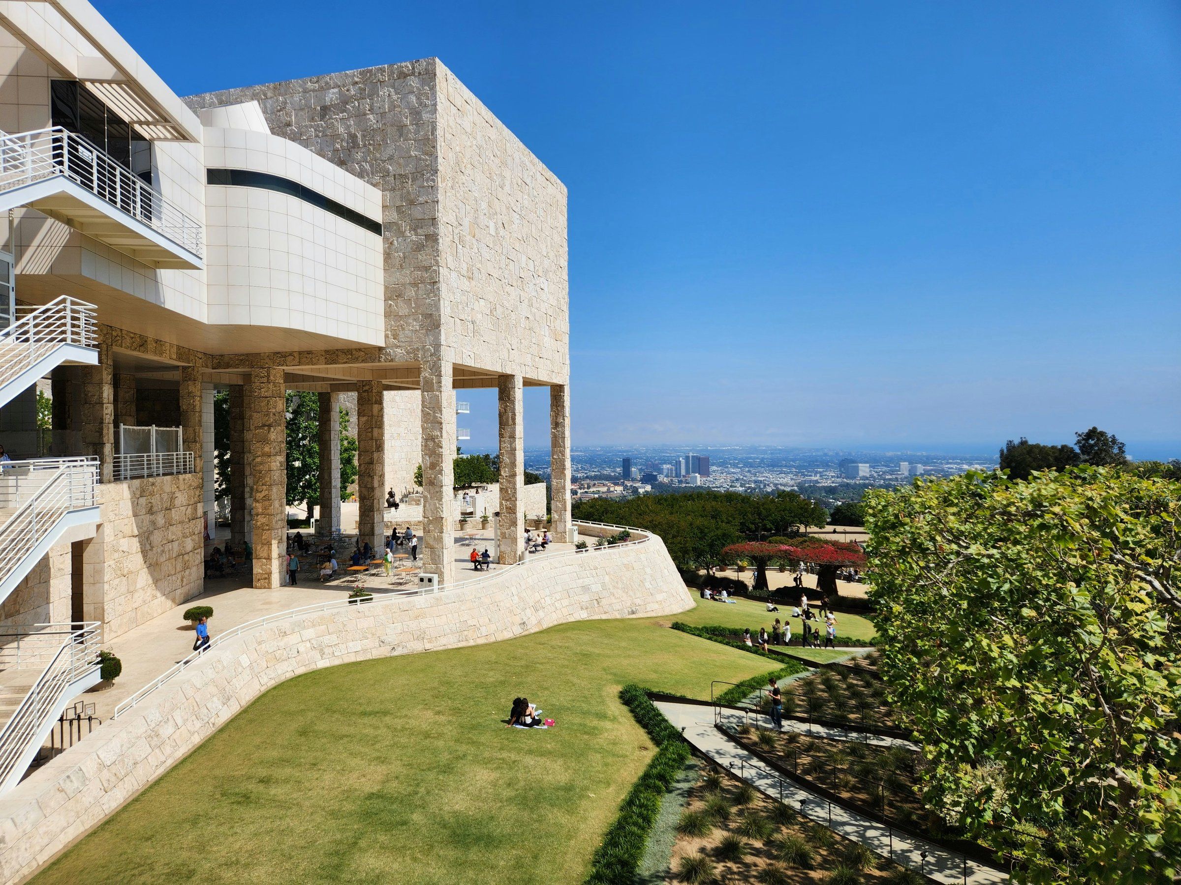 Stone terraces and a lawn above Los Angeles, with the city and ocean on the horizon